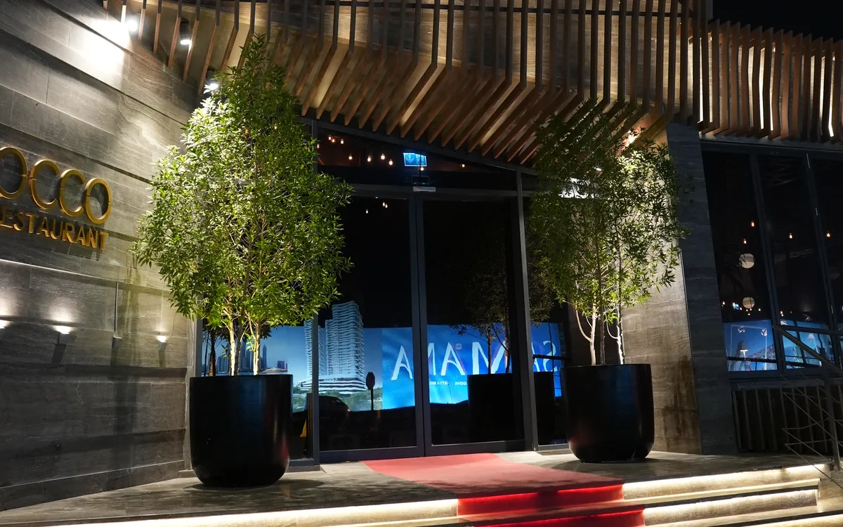 The entrance of OCCO Hessa at night with the lit OCCO sign and red carpet steps