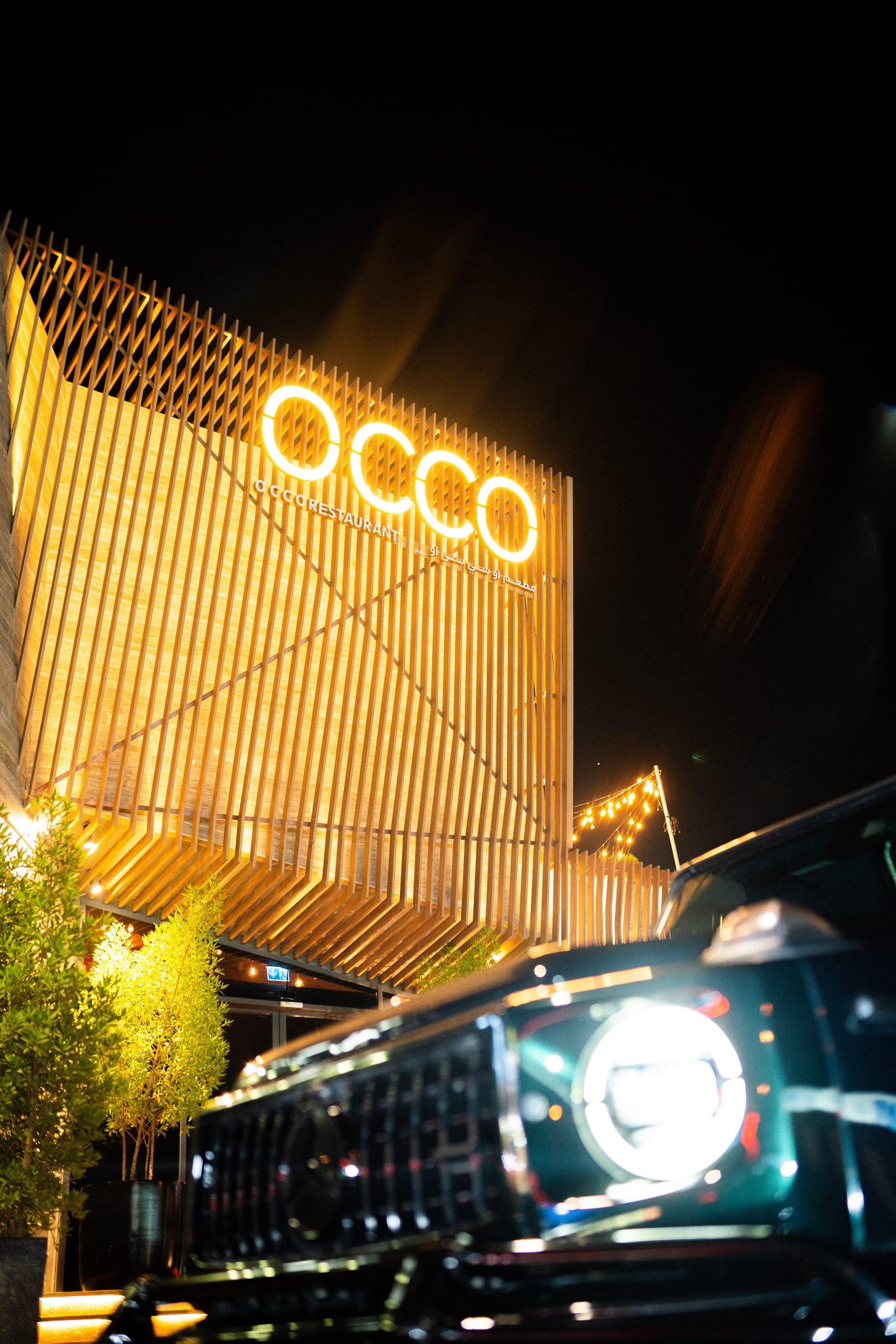 The OCCO Hessa facade at night with its illuminated OCCO signage