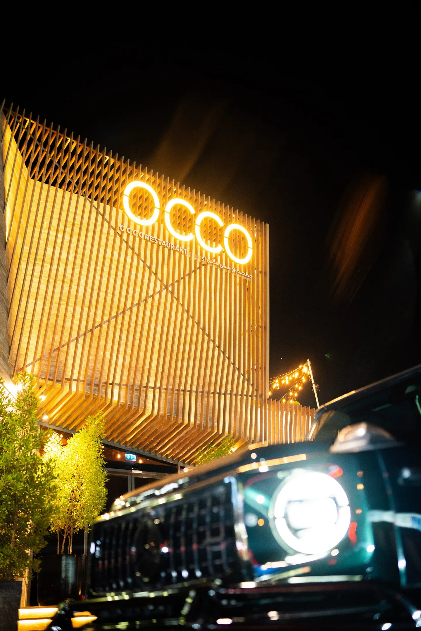 The OCCO Hessa facade at night with its illuminated OCCO signage