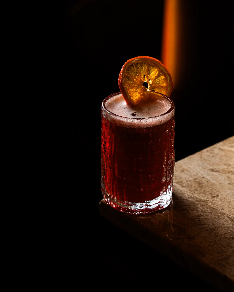 A red signature cocktail with a dried orange slice at OCCO Business Bay