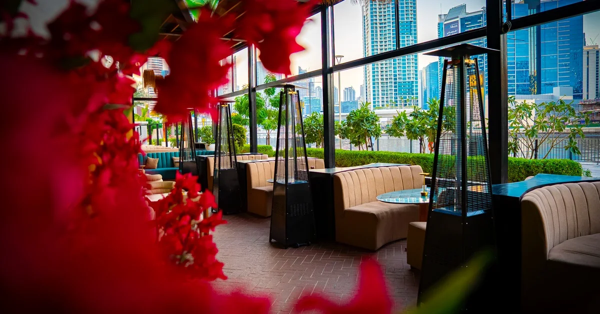 OCCO Business Bay room by the glass wall with red blossom and the Business Bay towers outside